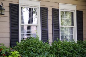 Two windows on a home with black colonial shutters