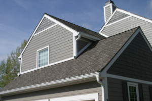 Exterior view of home with gray roofing and siding, and a white gutter system.