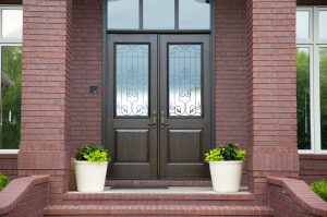 Residential home with dark brown entry doors and flower pots
