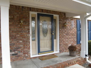 Front view of home with brick exterior, white porch pillars, and a beige front entry door with 2 side lites.