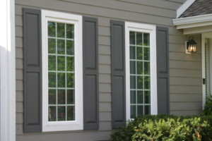 Residential home with gray siding, white windows, and shrubbery