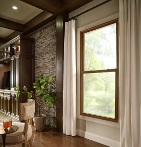 Living room with double-hung windows flanked by cream colored curtains 