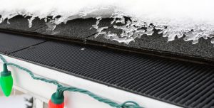 Gutter guard with Christmas lights and snow around it